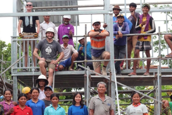 group of volunteers and local community members posing together on a construction site platform