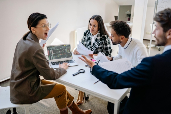 Four interns engage in a lively discussion while analyzing data on a laptop in a conference room.