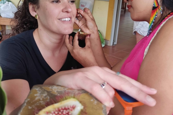 Tribal woman giving face paint to intern.