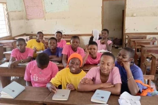 Young girls in B-GILD shirts attentively participate in an online session, highlighting their commitment to tech and digital skills learning.