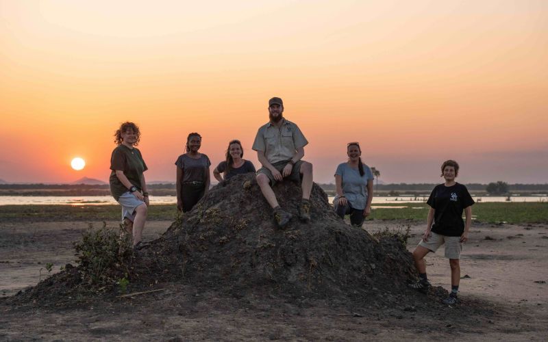 Participants in Lilongwe on top of a rock in front of a setting sun.