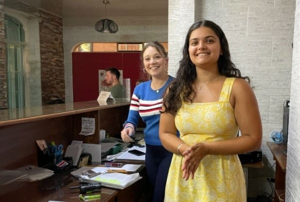 Two interns smiling while working at a reception desk in a tourism office