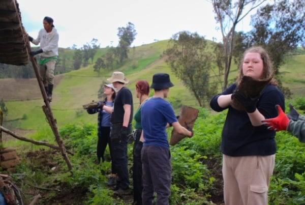 Interns work together to pass clay tiles for the restoration of a rural structure.