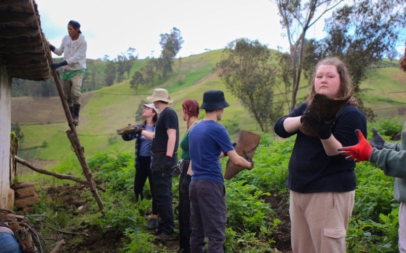 Interns work together to pass clay tiles for the restoration of a rural structure.