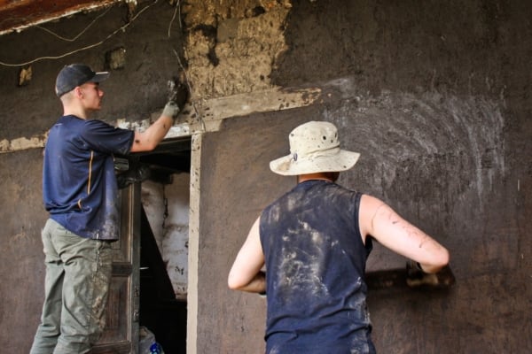 Interns coat a mud wall with a fresh layer of earthen plaster.