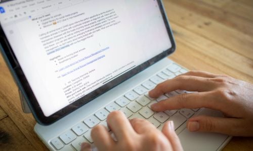 Hands typing on a tablet with a white keyboard