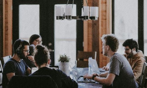 Group working together at a table with laptops in a shared workspace