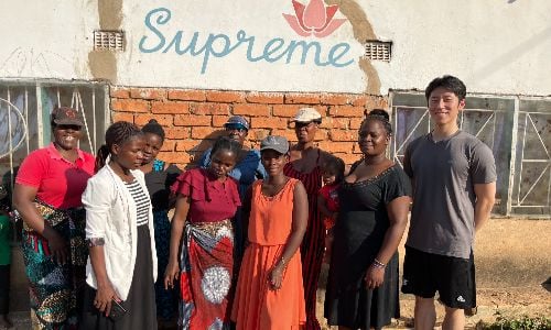 Larger group posing together in front of the Supreme workshop