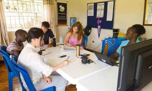 Five people sitting around a table. Several are taking notes.