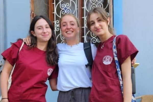 Three smiling women with their arms around one another.