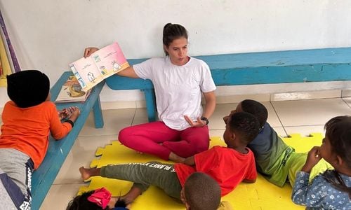 An intern reading a book to some children.